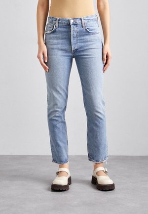 Lyseblå jeans i denim med høy midje, rette ben og frynsete falder. Kombinert med kremfargede sko med tykk såle og spenne-detalj.