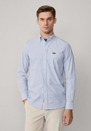Langärmliges Button-Down-Hemd in hellblau-weißen Streifen, mit kleinem Markenlogo auf der Brust und klassischem Kragen-Design.