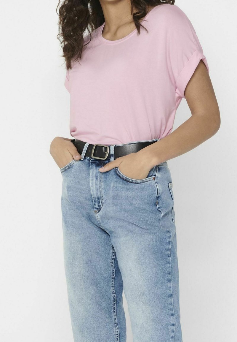 T-shirt rose à manches courtes assorti à un jean taille haute bleu clair, avec une ceinture en cuir noire et des manches retroussées.