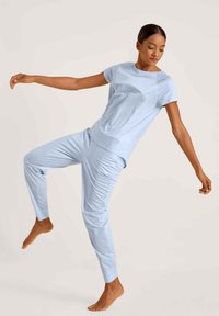 Helles blaues Sportoutfit bestehend aus einem kurzärmeligen Oberteil und tapered Hosen, mit einer glatten Textur und einfachem Design.