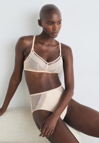 Beige mesh bra with vertical and dotted patterns, paired with high-waisted beige briefs featuring similar mesh accents. Smooth texture.