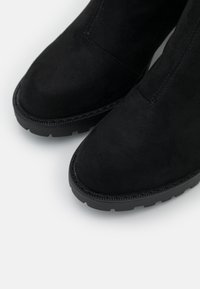 Stivaletti alla caviglia in suede nero con punta tonda, caratterizzati da una parte superiore texturizzata, una finitura liscia e una robusta suola in gomma nera.