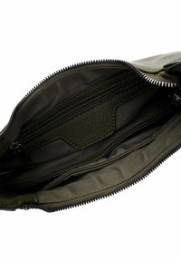 Interno di una borsa in pelle verde con un compartimento con zip, dettagli testurizzati e una fodera in tessuto liscio, dotata di più tasche per l'organizzazione.