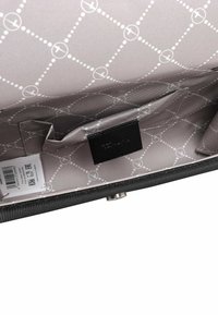 Svart handväska inuti med en slät yta och ljusgrå foder, cirkulärt och prickigt mönster, läderetikett och kortfack.