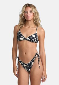 Bikini noir avec un motif floral blanc, présentant un haut triangulaire et un bas noué sur les côtés. Tissu doux avec des bretelles ajustables pour un bon ajustement.