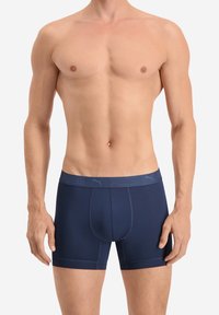 Marineblaue Boxershorts aus dehnbarem Material mit schmaler Passform, ausgestattet mit einem weichen Bund, der das Puma-Logo in einer kontrastierenden Farbe trägt.