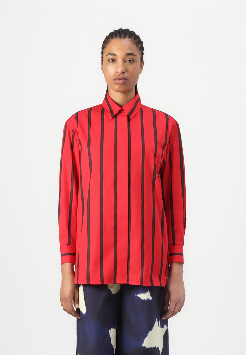Camicia rossa a maniche lunghe con strisce verticali nere, dotata di colletto a punta e polsini con bottoni. Tessuto liscio con una vestibilità strutturata.