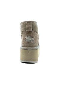 Stivaletto in suede marrone con finitura testurizzata, punta rotonda e suola piatta spessa. Presenta una linguetta sul retro e un logo EMU Australia.