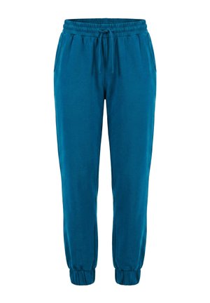 Mano descansando dentro del bolsillo de unos pantalones azules con bordado "take a break" cerca de la cintura elástica y una pequeña etiqueta de tela negra.