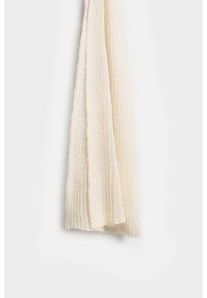 Biała dziana chusta o fakturowanym wykończeniu, cechująca się lekkim, miękkim materiałem i wydłużonym kształtem, wisząca na neutralnym tle.