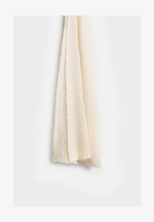Biała dziana chusta o fakturowanym wykończeniu, cechująca się lekkim, miękkim materiałem i wydłużonym kształtem, wisząca na neutralnym tle.