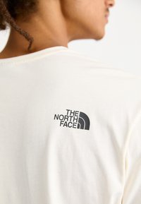 The North Face M VARSITY GRAPHIC RELAXED SS TEE - Triko s potiskem - white dune