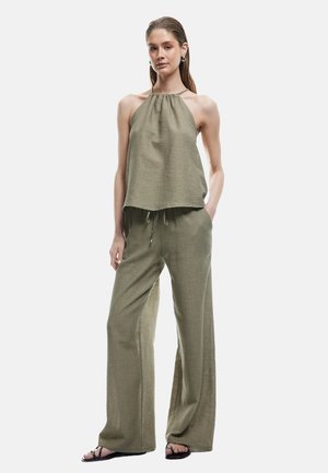 Completo in lino verde oliva composto da due pezzi, con top a collo alto e pantaloni a gamba larga con vita con cordino. Semplice texture e design.