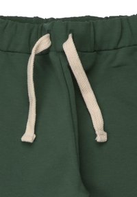 Dunkelgrüne Sweatpants mit weichem Textil, elastischem Bund und cremefarbener Kordel mit strukturierten Enden.