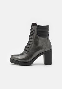 Botín negro y plateado con un acabado brillante, diseño con cordones, cuello acolchado y suela de tacón grueso.