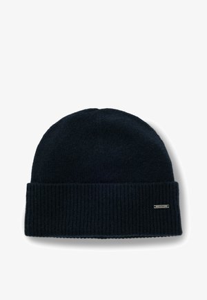 Gebreide donkerblauwe beanie met een geribde boord en een klein zilveren logolabel. Gladde textuur, afgeronde top.