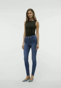 Μαύρο αμάνικο μπλουζάκι, μπλε skinny jeans και ανοιχτό μπλε ψηλοτάκουνα παπούτσια με κο尖η κεφαλή. Λείο υφή, εφαρμοστή σχεδίαση, με μινιμαλιστικές νότες.