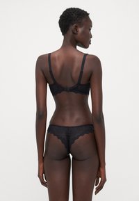 Black lace bra and thong set with scalloped edges, adjustable straps, and a hook closure, featuring a semi-sheer texture.