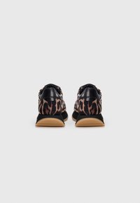 Baskets imprimées léopard avec des accents en cuir noir, forme arrondie, tige texturée et semelles en caoutchouc beige et noir. Le design met l'accent sur le style décontracté.