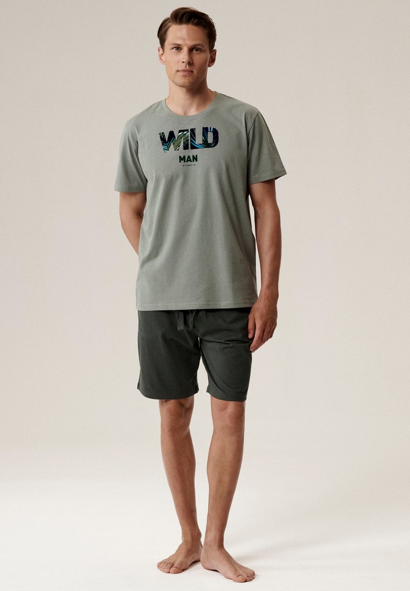 Zielona koszulka z krótkim rękawem z grafiką "WILD MAN", w połączeniu z ciemnozielonymi szortami, wykonana z miękkiego materiału, idealna na co dzień.