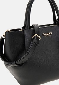 Sac à main en cuir granuleux noir avec doubles poignées et bandoulière amovible. Éléments en métal doré et logo. Fermeture à glissière.