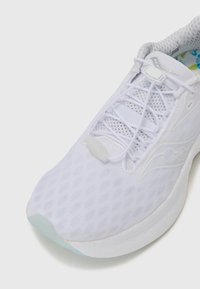 Zapatilla blanca para correr con parte superior de malla, patrón texturizado, suela flexible y un interior azul en contraste. Incluye un sistema de cordones tradicional.