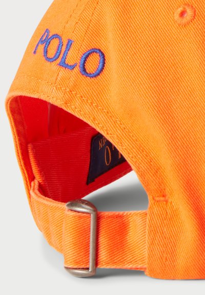 Oranžinė medvilninė kepurė su mėlynu siuvinėjimu "POLO", reguliuojama metaline sagtimi nugaroje ir lygiu paviršiumi.