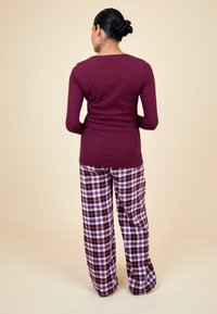 Mauve longsleeve top gecombineerd met geruite pyjamabroek in bordeaux, wit en blauw. Losvallend, zacht materiaal, ontspannen ontwerp.