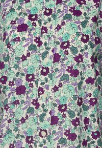 Kukkakuosinen paita, jossa monivärinen kuvio turkoosia, purppuraa ja valkoista, napitettava edestä ja sileä kangaspinta.