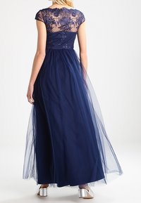 Abito lungo navy con un corpino in pizzo trasparente, ricami floreali e una gonna in tulle fluenti. Presenta maniche a cappuccio e una vita aderente.