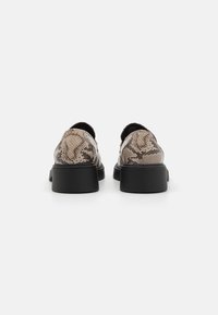 Scarpe stampa serpente con finitura testurizzata, punta rotonda e tacco basso nero a blocco. La vista posteriore mostra linee curve e lisce con un motivo unico.