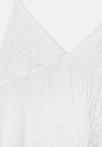 Tessuto bianco e strutturato con un motivo arricciato, caratterizzato da un scollo a V e elementi di design sovrapposti.