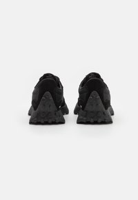 Schwarze Sportschuhe mit einem Obermaterial aus Mesh, Wildlederakzenten, einer einzigartigen dreieckigen Sohle mit strukturierten, abgerundeten Noppen und einem gepolsterten Schaft für zusätzlichen Komfort.