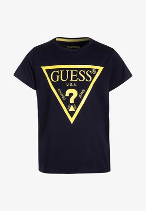 Camiseta azul marino de manga corta con un gran logo amarillo de Guess y un signo de interrogación dentro de un triángulo invertido en la parte delantera.