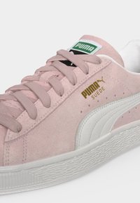 Ροζ σουέντ αθλητικό παπούτσι Puma με λευκή γραμμή, μπεζ κορδόνια και χρυσό λογότυπο Puma Suede στη πλευρά.