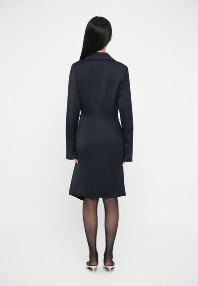 Rochie ajustată bleumarin cu mâneci lungi, rever ascuțit și detalii cu nasturi; material neted și lungime deasupra genunchiului cu un tiv ușor evazat.