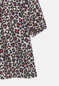 Harmaa leopardi-kuosiset mekko kultaisilla, punaisilla ja mustilla pilkuilla; pehmeä kangas; taitettu hiusdetail; hemmetissä on pyöreä logo.