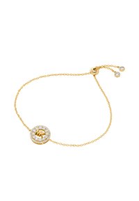 Bracciale in oro con un centro circolare, adornato da un alone di gemme trasparenti e un dettaglio in oro testurizzato al centro.