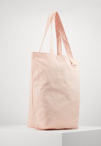 Różowa torba płócienna z nadrukiem "AIR" na biało, z dwoma solidnymi uchwytami i prostą, niestrukturalną budową.