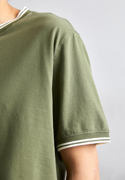 Camicia a maniche corte verde oliva con texture, colletto tondo, caratterizzata da accenti a righe bianche e verde scuro sui polsini.