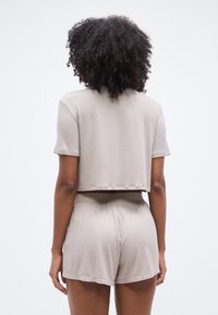 Ensemble deux pièces beige clair côtelé comprenant un haut court à manches courtes et un short taille haute, confectionné dans un tissu doux et texturé.