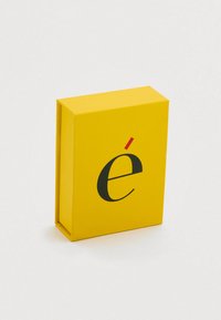 Boîte rectangulaire jaune avec une finition lisse, présentant un "é" stylisé en noir dans une police moderne. Design compact aux bords nets.