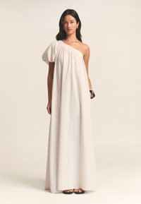 Abito maxi monospalla in tessuto beige chiaro, con un corpetto ampio e arricciato e una gonna fluente, completato da un dettaglio con manica a sbuffo.