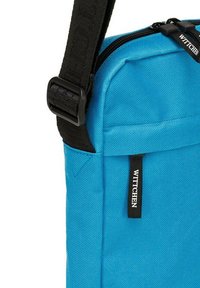 Borsa a spalla in tessuto blu con superficie testurizzata, tracolla nera regolabile e cerniera con etichetta logo. Design compatto e funzionale.