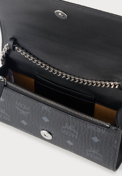 Μαύρο πορτοφόλι MCM με αλυσίδα ασημί, θήκη με φερμουάρ, κλείσιμο με κουμπί και πολλαπλές θήκες για κάρτες στο εσωτερικό.