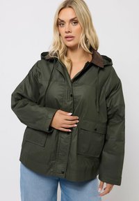 Veste légère vert olive avec capuche, col en velours côtelé, fermeture à boutons sur le devant et deux poches latérales. Texture lisse, coupe ample.