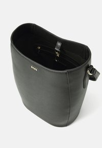 Sac fourre-tout en simili cuir noir avec une texture lisse, une forme légèrement conique, un détail de logo doré et une poche zippée intérieure.