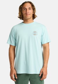 T-shirt in cotone azzurro chiaro con collo a giro e maniche corte, caratterizzato da una stampa circolare del logo sul lato sinistro del petto.