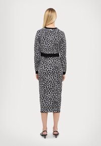 Robe midi à imprimé léopard avec manches longues, ceinture noire et poignets côtelés. Tissu doux avec une coupe ajustée.