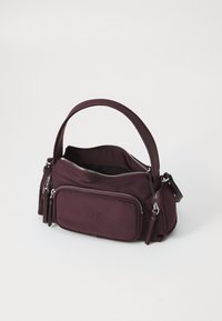 Borsa Calvin Klein di colore viola scuro con più scomparti con cerniera e un'unica maniglia superiore su uno sfondo bianco.